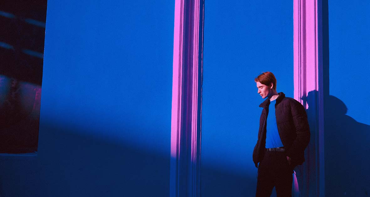 Man standing against a blue and pink wall