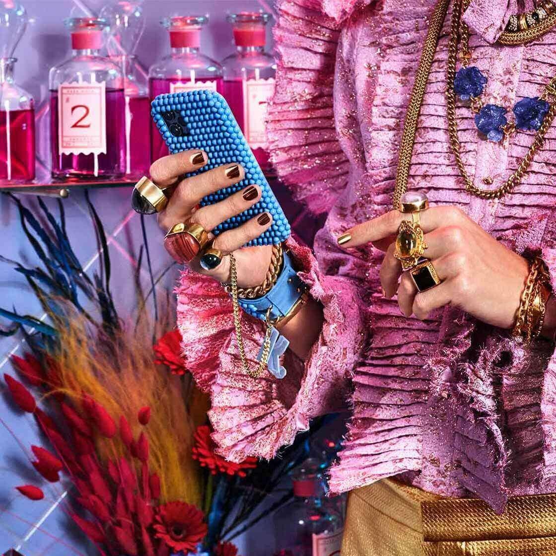 Woman in a pink ruffled shirt, holding a mobile phone in a blue case